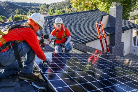 Workers install solar panels on a rooftop