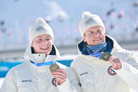Johannes Høsflot Klæbo and Einar Hedegart show off their gold medals after their cross-country team sprint win.