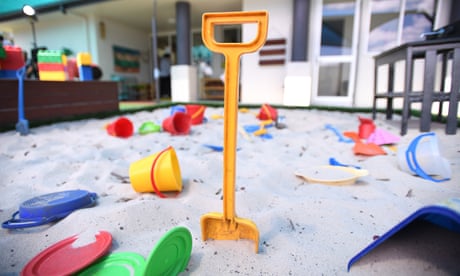 A yellow spade is stuck upright in a children's sand pit surrounded by other toys at a childcare centre
