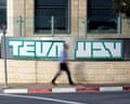 A man walks past the Teva Pharmaceuticals logo sign in Jerusalem