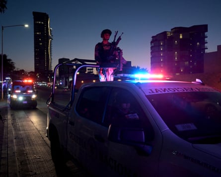 Night view of military person on top of vehicle with flashing lights