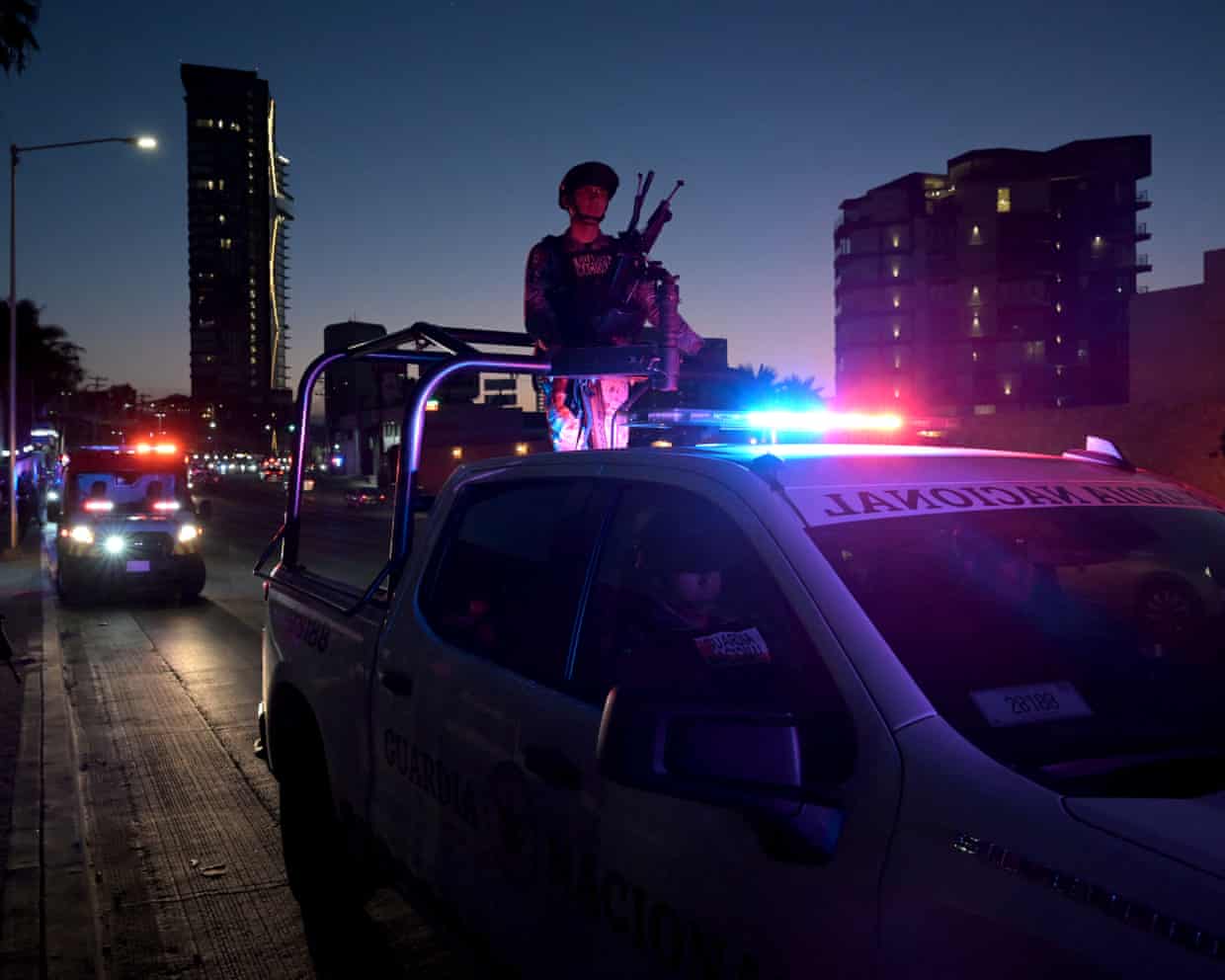 Night view of military person on top of vehicle with flashing lights