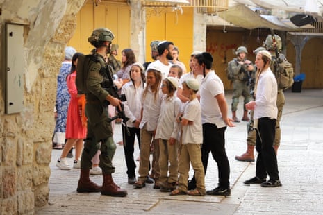 Jewish settlers tour the Old City in the occupied-West Bank city of Hebron under the protection of Israeli soldiers on 18 May.