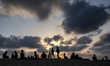 Clouds are pictured behind children at sunset at a camp housing displaced Palestinians in Rafah in the southern Gaza Strip. Follow live for the latest updates in the Middle East crisis.