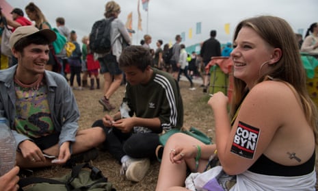 A young woman wears a Jeremy Corbyn sticker on her arm at Glastonbury festival.