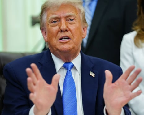 President Donald Trump in a dark suit and blue tie gestures with both hands while speaking