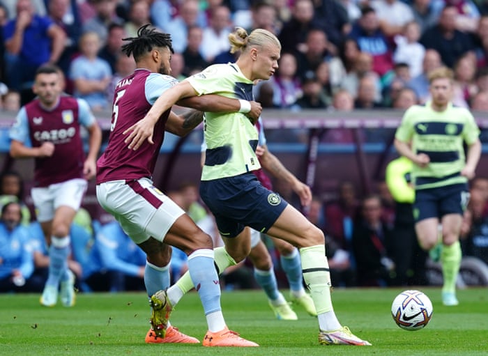 Tyrone Mings trata con Erling Haaland.