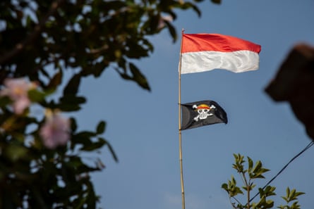 A pirate flag from the Japanese anime, One Piece, is installed on a bamboo pole under the national flags, red and white, at a motorcycle repair shop in Indramayu, West Java province, on August 9, 2025.