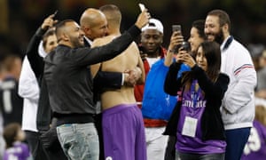 Real Madrid coach Zinedine Zidane celebrates with Karim Benzema as people take selfies around them.