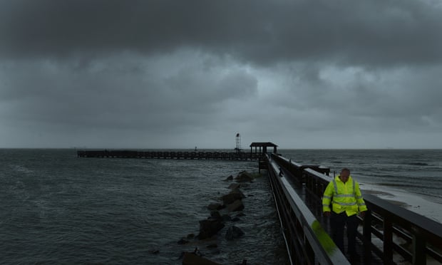 A Cape Charles police officer walks back to his vehicle after checking out the fishing pier in Virginia on Saturday as the storm intensified along the Atlantic coast.