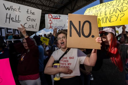 People hold signs protesting against a data center