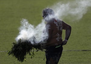 An Aboriginal man carries the fire for a smoking ceremony.