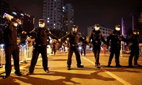 Police officers stand guard as people protest coronavirus disease restrictions in Beijing on 27 November