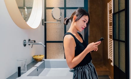 Mulher jovem usando telefone celular no banheiro