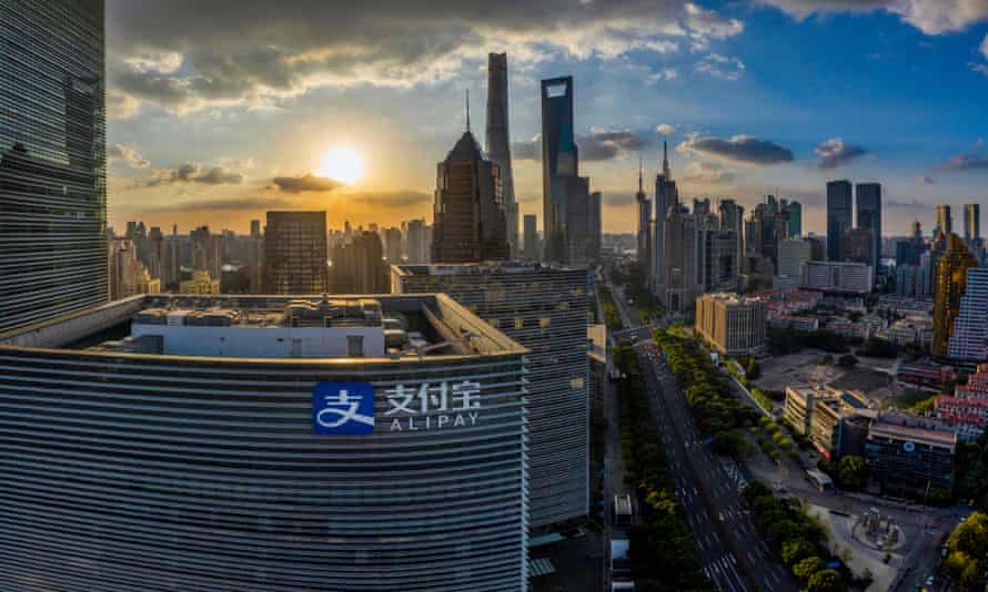 High level view of skyscrapers in front of a sunset in Shanghai.  A building with the Alipay logo is closest to the camera