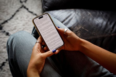 Closeup of Emma’s hands holding her mobile phone, with a lot of text on the screen