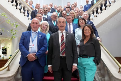Nigel Farage with Brian Collins (left) and Linden Kemkaran (right), with other Reform UK councillors standing behind them, as they all posed for a photograph when Farage visited the council in July..