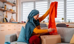 young muslim woman at home unpacking package with a new scarf.