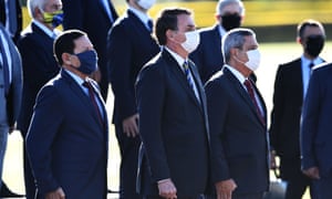 Jair Bolsonaro (C), his Vice-President Hamilton Mourao (L) and Chief of Staff Walter Souza Braga Netto (R) wear face masks as they attend the flag-raising ceremony before a ministerial meeting at the Alvorada Palace in Brasilia in May.