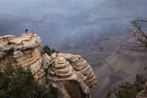 A couple take pictures from an outcropping as smoke fills the Grand Canyon