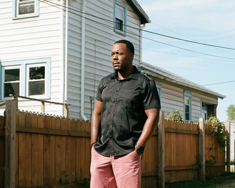 man in black shirt and pink shorts stands outside for a portrait