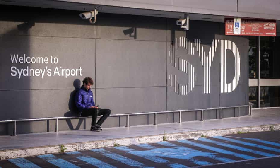 A man sits outside the departures area of a largely empty Sydney International Airport.