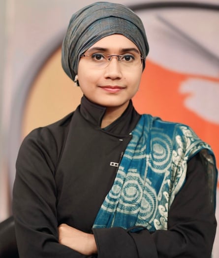 Portrait of a young woman wearing a turban-like headscarf with a scarf on her shoulder and glasses