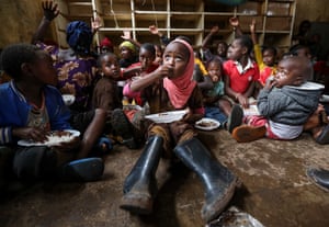 Displaced children eat a meal prepared by volunteers