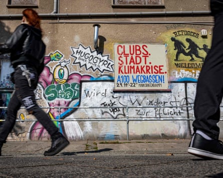 People walking past a mural in German reading “Clubs instead of climate crisis”.