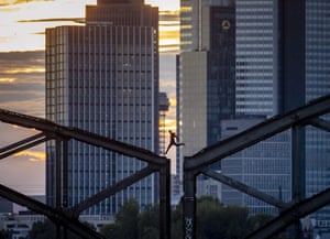 A parkour runner jumps on a railway bridge in front of buildings in the Frankfurt banking district.