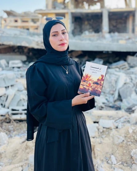 Aya Abu Nasr holding a book with the rubble of a collapsed building behind her