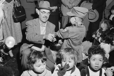 a man rolls up the sleeve of a toddler as others sit nearby