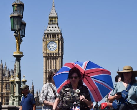 A woman carries an umbrella to shield herself from heat as she walks on Westminster Bridge.