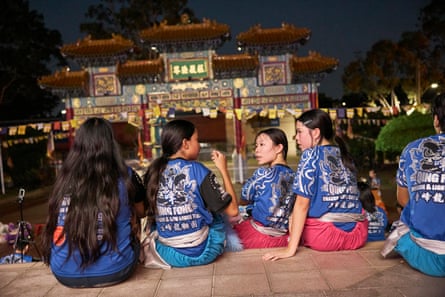 Young dancers wearing Quing fong T-shirts watch final dance rehearsals outside the temple