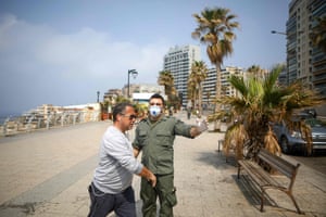 A Beirut municipality policeman ask a jogger to leave the area in the Lebanese capital on Monday, a day after the government urged people to stay at home for two weeks