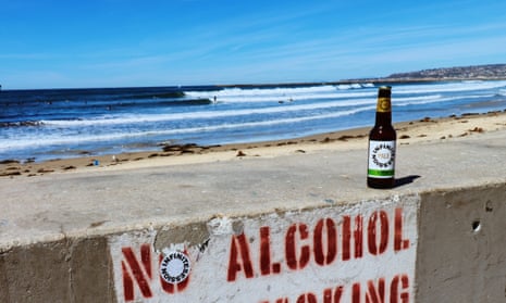 An Infinite Sessions beer on a 'no alcohol' sign by a beach.