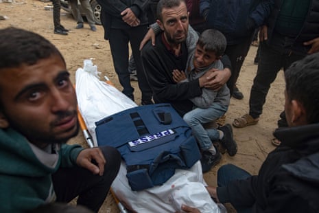 Relatives of Palestinian journalist Ahmed Al-Shayah mourn next to his body after he was killed in an overnight Israeli airstrike, at Nasser hospital in Khan Younis, southern Gaza Strip, 16 January.