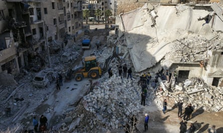 Rescuers search rubble in a street of ruined buildings