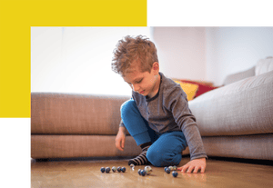 Young boy playing with marbles on living room floor