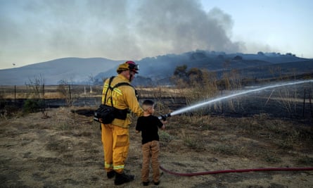 Capt Eli Cronbach, a firefighter with the city of Napa, lets Dylan Ramirez, six, spray water as crews work to contain the American Fire in American Canyon, California, early this month.