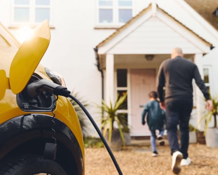 Electric car charging on driveway outside house