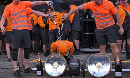 Lando Norris is soaked with champagne by his team members.