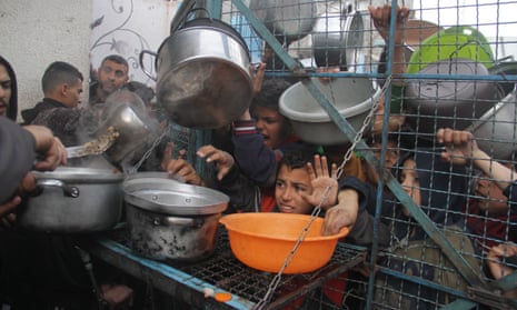 Palestinians hold empty containers to receive food distributed by aid organizations in Jabalia, Gaza on 18 March.|465x278.9641203703704