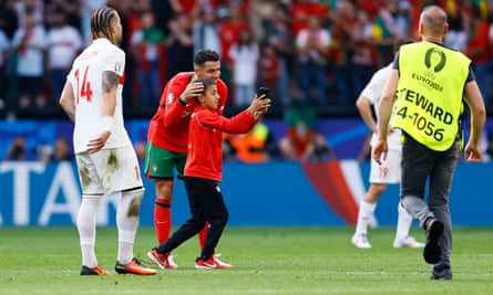 Cristiano Ronaldo poses for a picture with a young fan who ran on to the pitch.