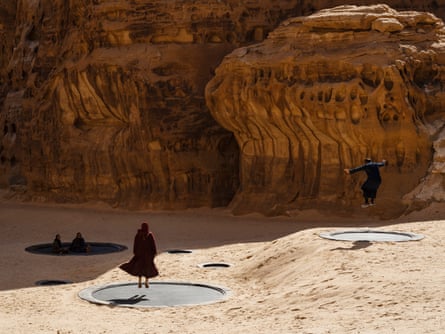 Άνθρωποι που πηδούν σε τραμπολίνα ενσωματωμένα στην άμμο της ερήμου