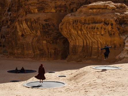 People jumping on trampolines embedded in the desert sand