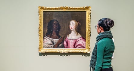 A woman looking at the painting Two Women Wearing Cosmetic Patches, featuring a black woman and a white woman from the 17th century.