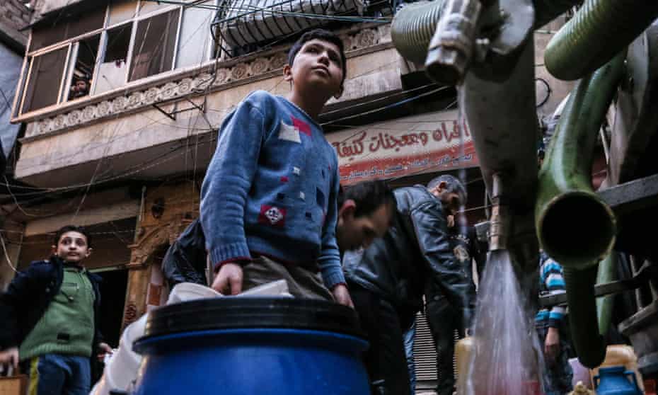Boys fill containers with drinking water from a tank in Salah al-Din, Aleppo.