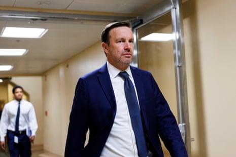 Senator Chris Murphy, in a dark blue suit and tie, walks through a corridor