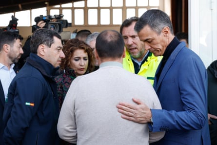 Sánchez (right) puts a hand on a man’s back as six people stand speaking together